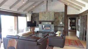 Un salón amplio con chimenea de piedra, sofás de cuero y televisor.