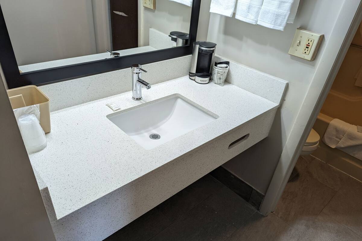 A modern bathroom with a white sink, chrome faucet, and a large mirror.