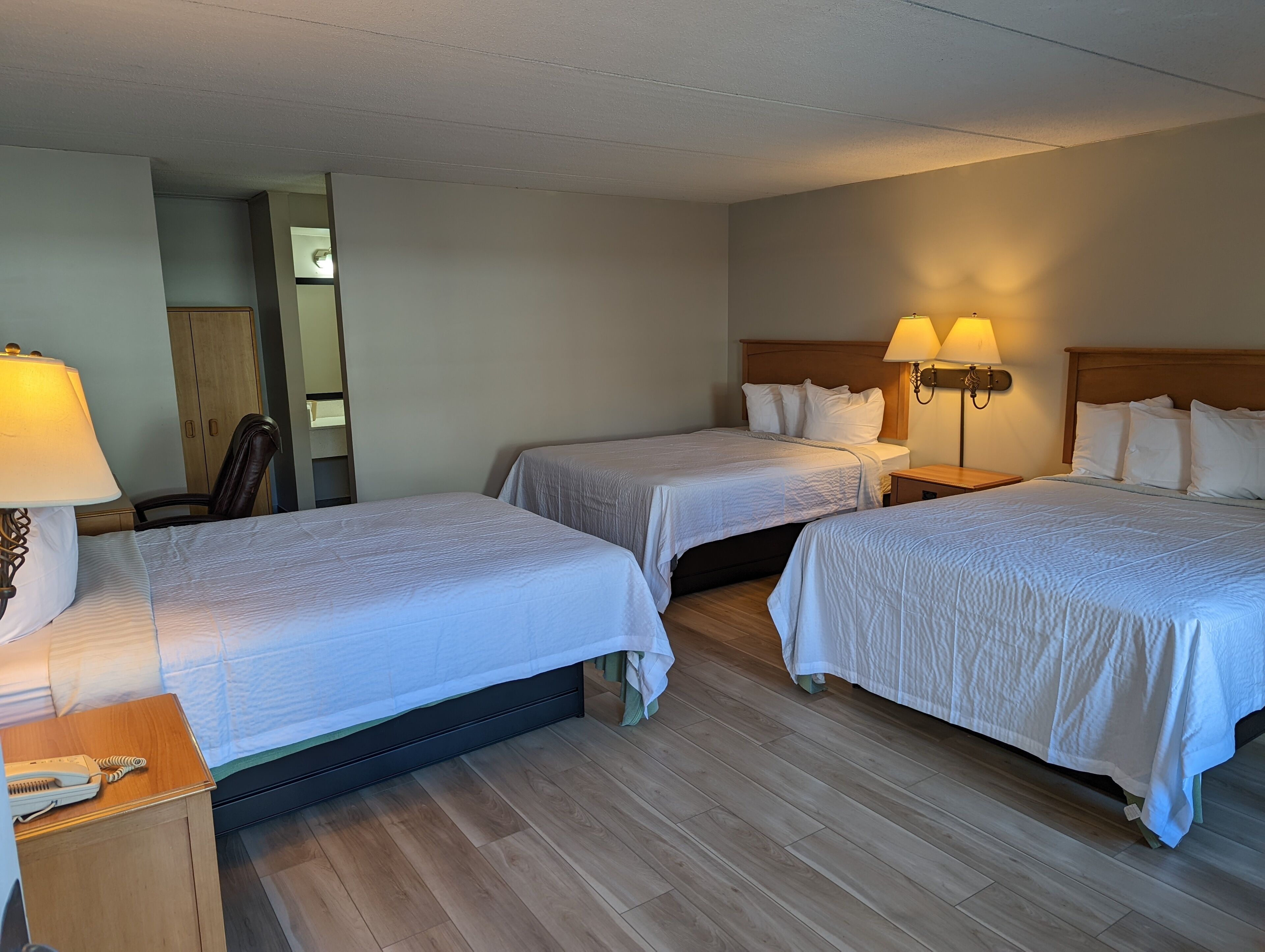 Une chambre d’hôtel avec deux lits, une table de chevet en bois avec un téléphone et une lampe fixée au mur.