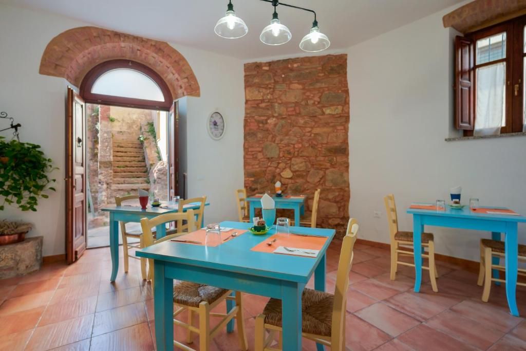 A dining area with blue tables and chairs, a stone wall, and a staircase leading to an outdoor area.