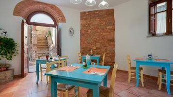 A dining area with blue tables and chairs, a stone wall, and a staircase leading to an outdoor area.