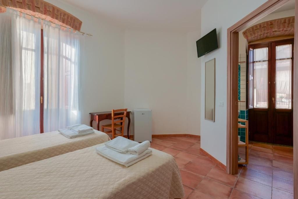 A hotel room with two beds, a desk, a chair, a television, and a door leading to a bathroom.