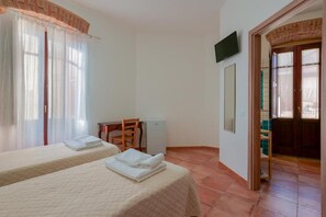 A hotel room with two beds, a desk, a chair, a television, and a door leading to a bathroom. - La Scala del Sale (Iglesias)