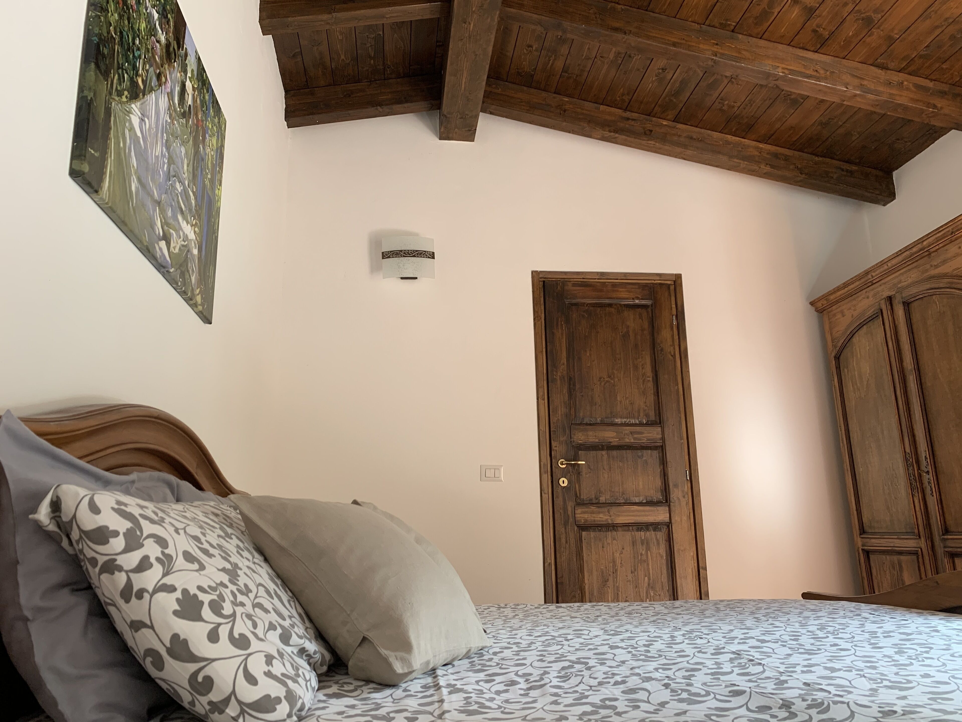 A bedroom with a bed, a wooden door, and a wardrobe.