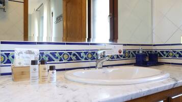 Baño con lavamanos blanco, azulejos estampados en azul y amarillo, y armarios de madera.