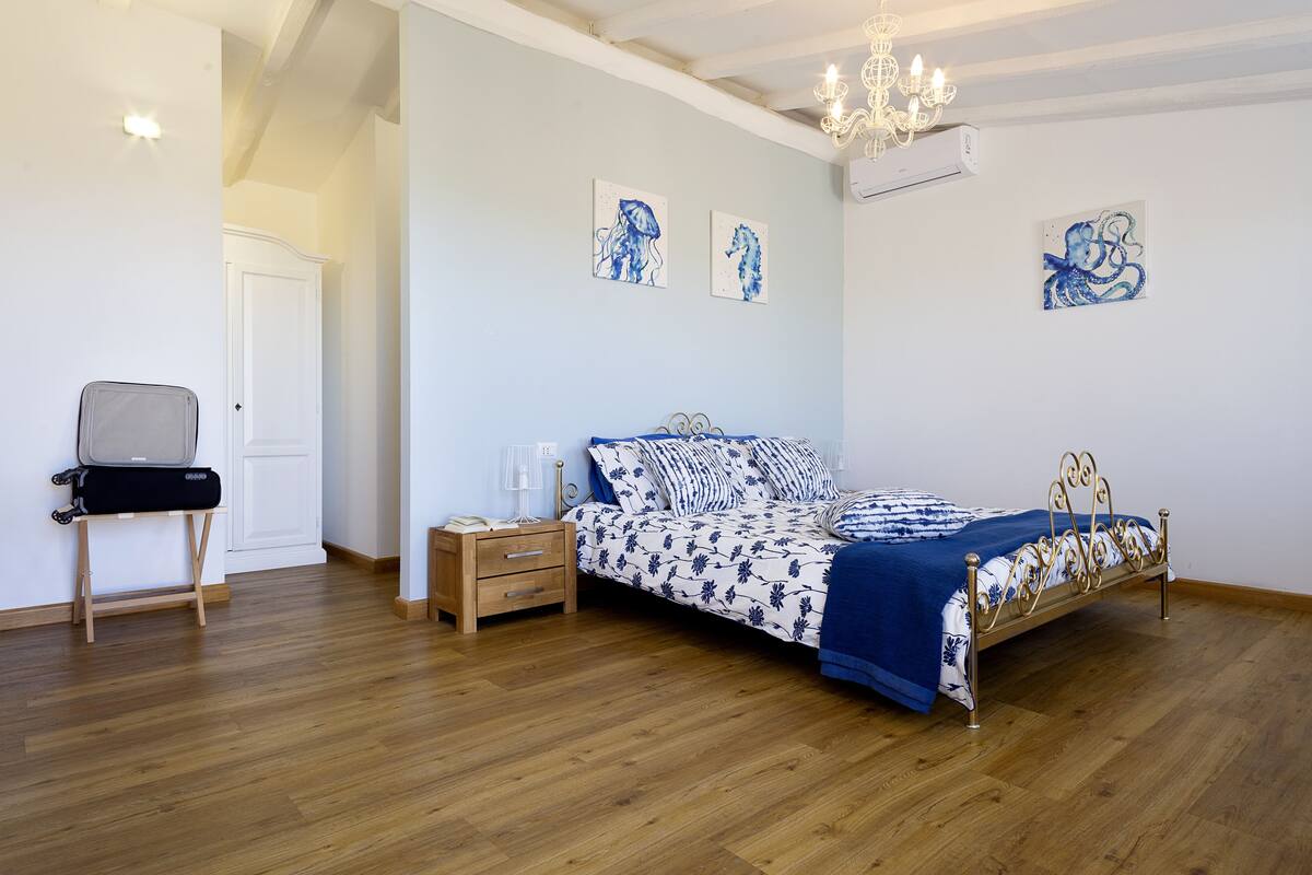 A bedroom with a bed, a nightstand, a chair, and artwork on the walls.