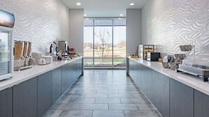 Una cocina moderna con armarios grises, una isla central y vistas amplias a través de grandes ventanales.