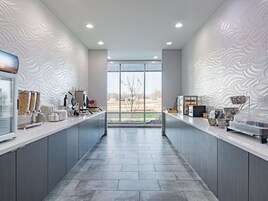 Una cocina moderna con armarios grises, una isla central y vistas amplias a través de grandes ventanales.