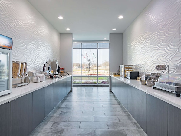 A modern kitchen with grey cabinets, a central island, and a view through large windows. - La Quinta Inn & Suites by Wyndham Dallas - Wylie (Wylie)