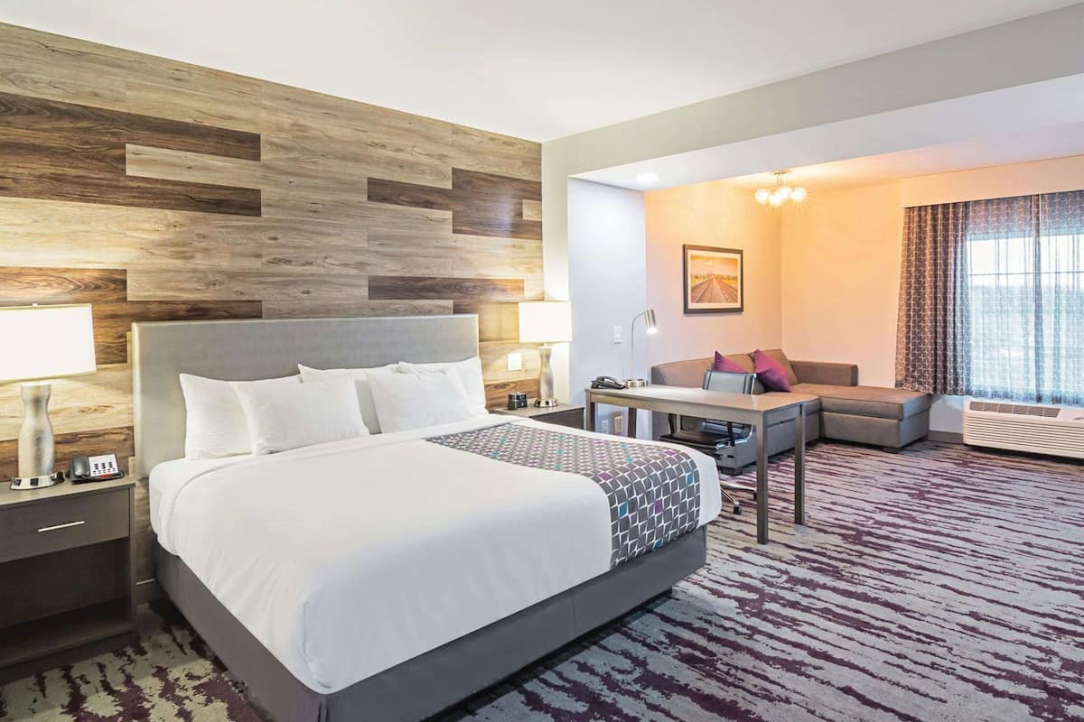 Een hotelkamer met een groot bed, een bureau, een bank en uitzicht op de omgeving.