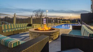 Zona junto a la piscina con un pozo de fuego, sillones de descanso y vistas a la piscina.