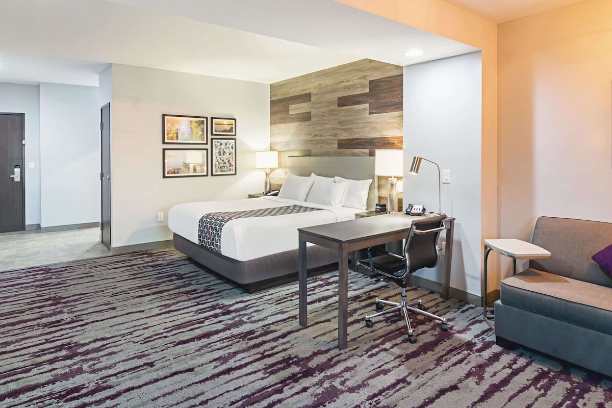 Een hotelkamer met een bed, een bureau, een stoel, een bank en een vloerbedekking.