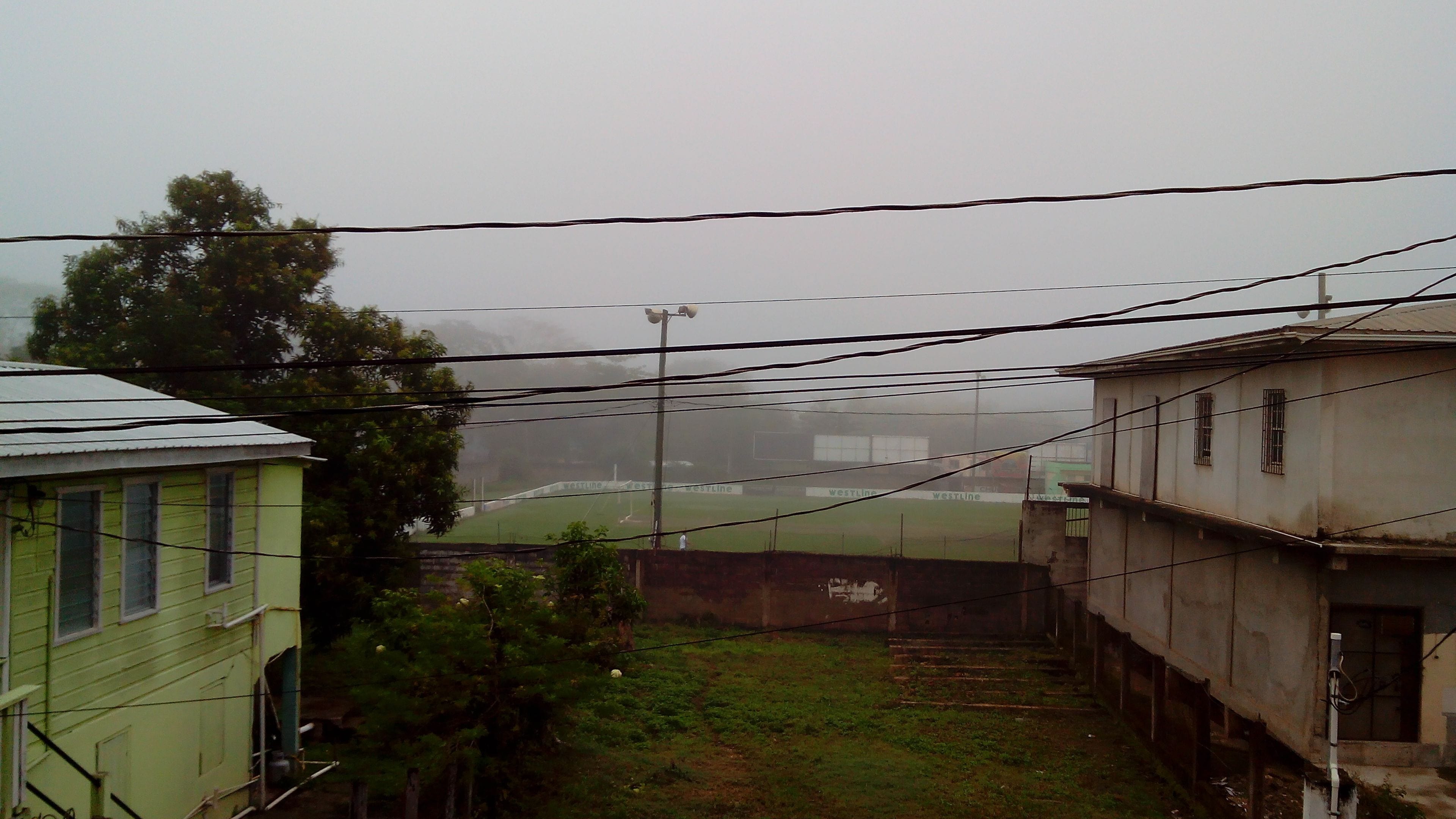 Área residencial com casas, um gramado e fios de eletricidade.
