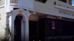 Um edifício de dois andares com uma varanda e uma placa que diz 'Western Guest House'.