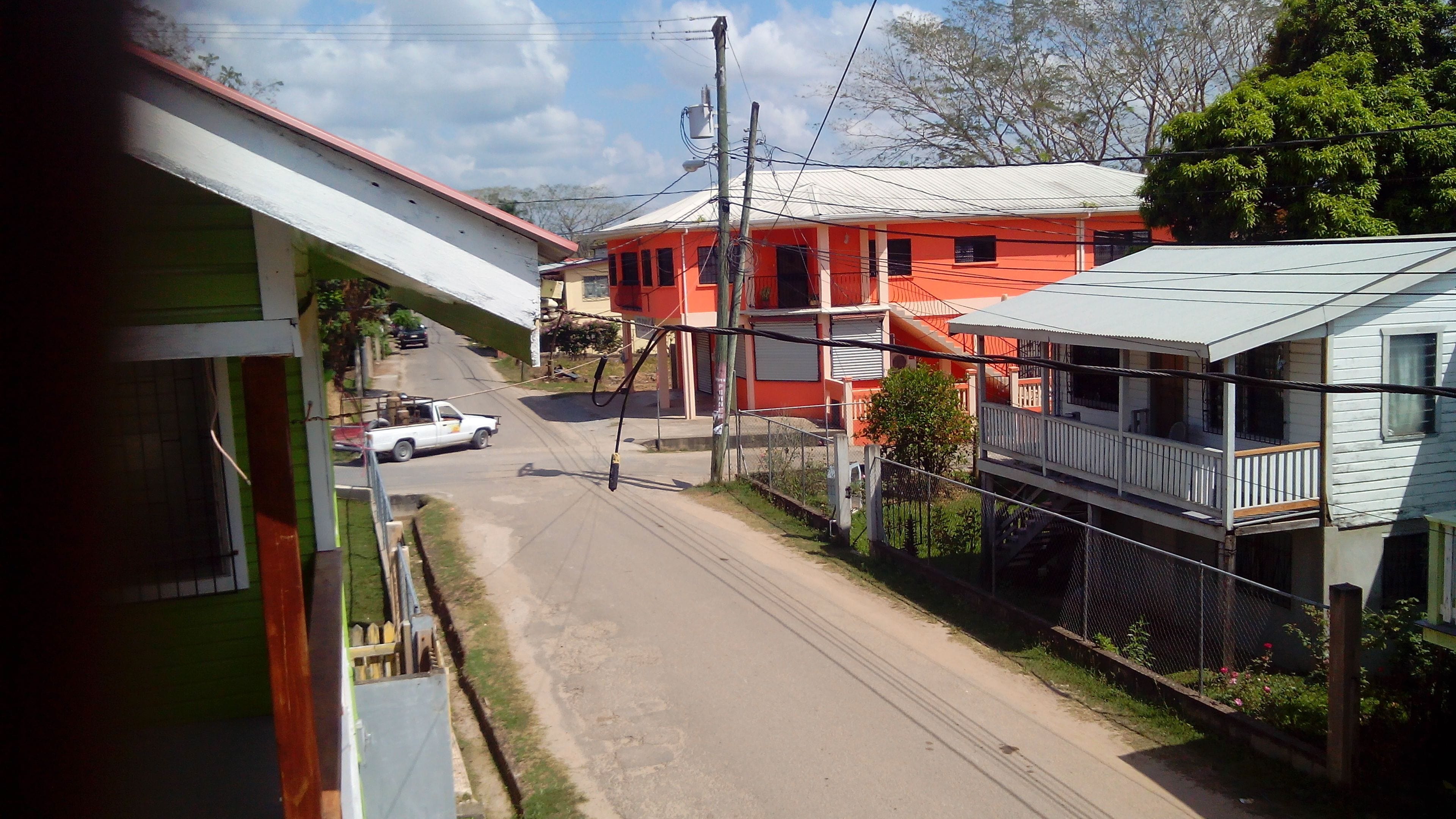 Vista de la calle con un edificio rojo, un camión blanco y un edificio verde.