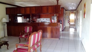 Uma sala de estar ampla, com um balcão de madeira e duas cadeiras listradas.