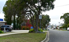 A street with a bike lane sign, parked cars, and a motel sign.