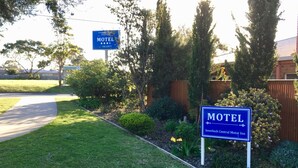 A motel sign with a clear view of the surrounding greenery and a paved road. - Inverloch Central Motor Inn (Inverloch)