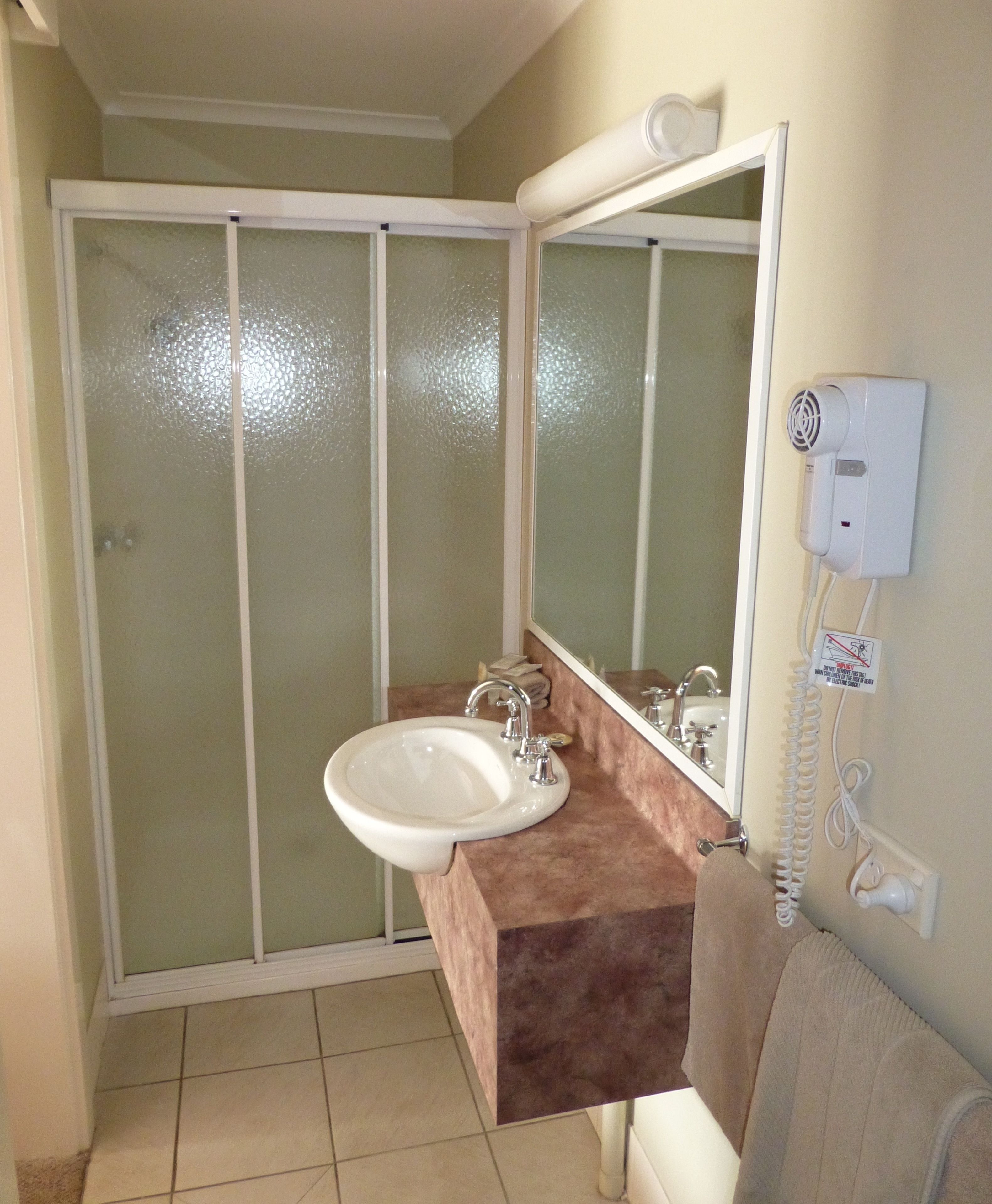 Un baño con un lavamanos blanco, un espejo y una toalla colgada en la pared.