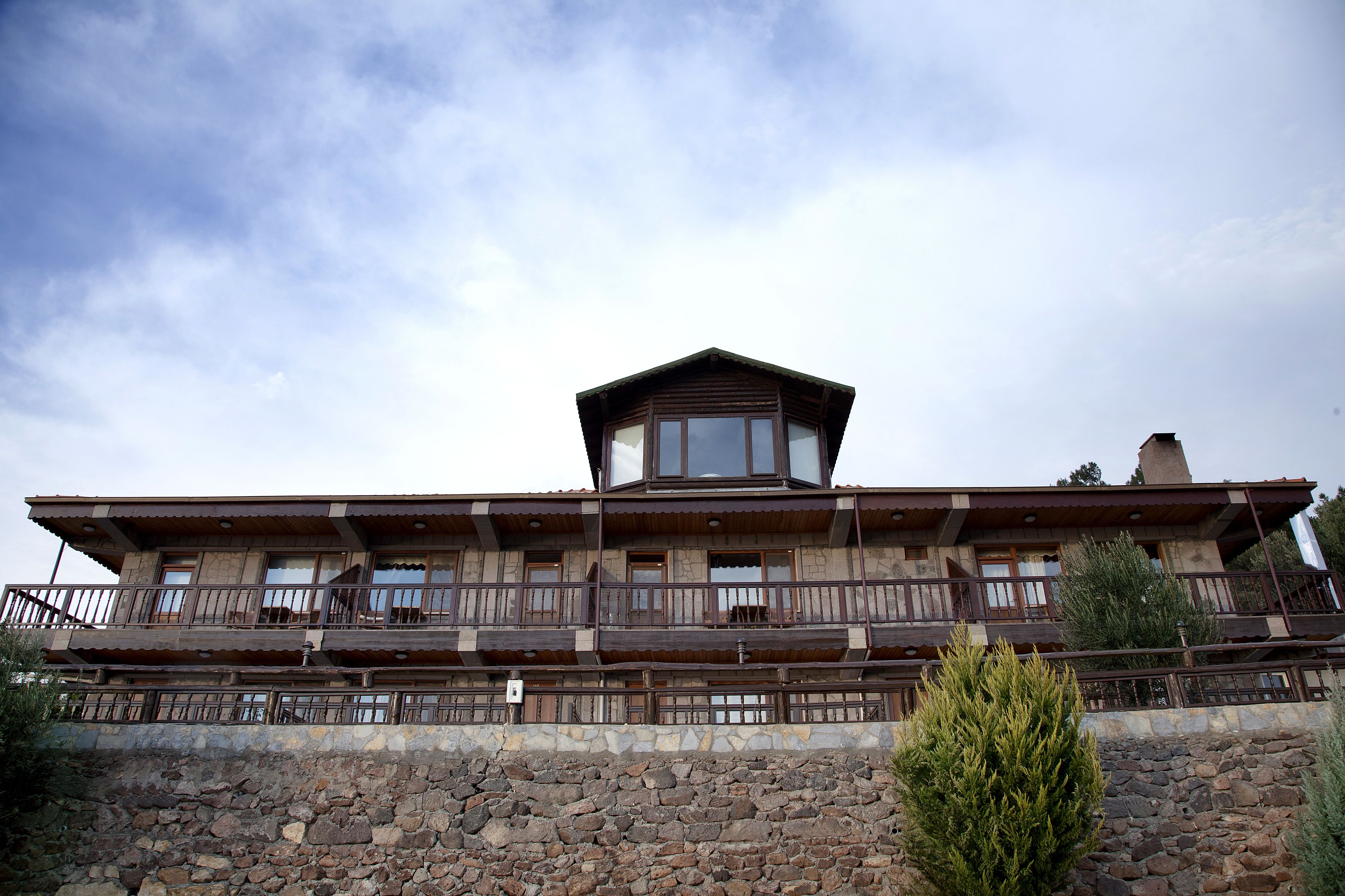 A multi-story wooden building with balconies, stone walls, and a clear sky.