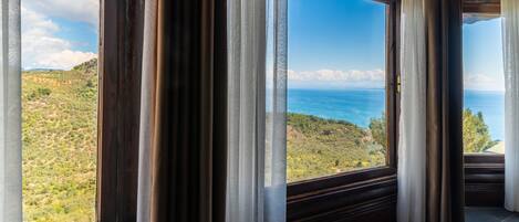 A room with a large window offering a view of a coastal landscape.