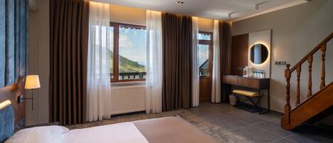 Habitación de hotel con una cama grande, un escritorio de madera, un espejo y vistas al exterior.