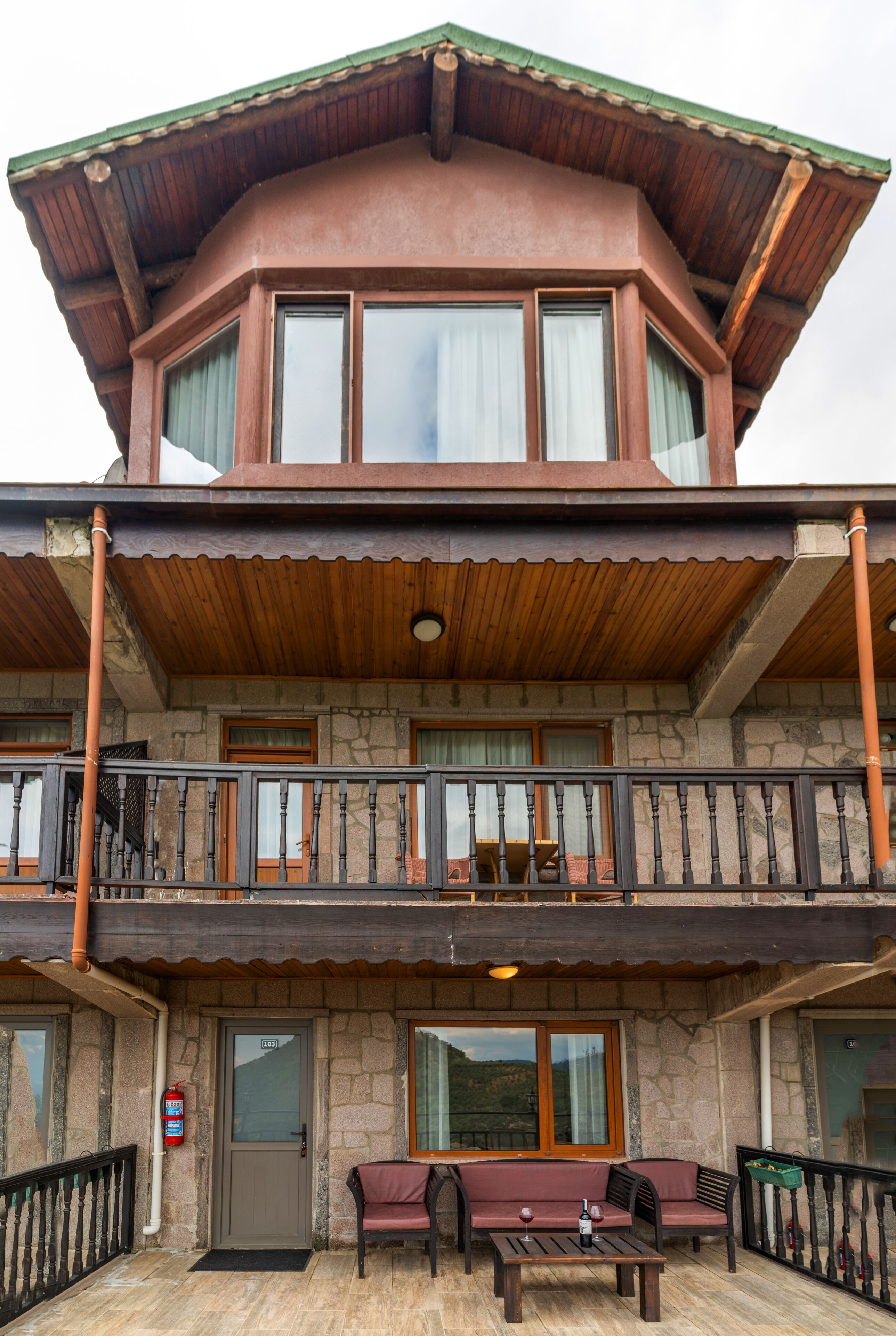 A two-story building with a balcony, stone walls, and a wooden roof.