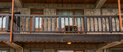 A two-story building with a balcony, stone walls, and a wooden roof.