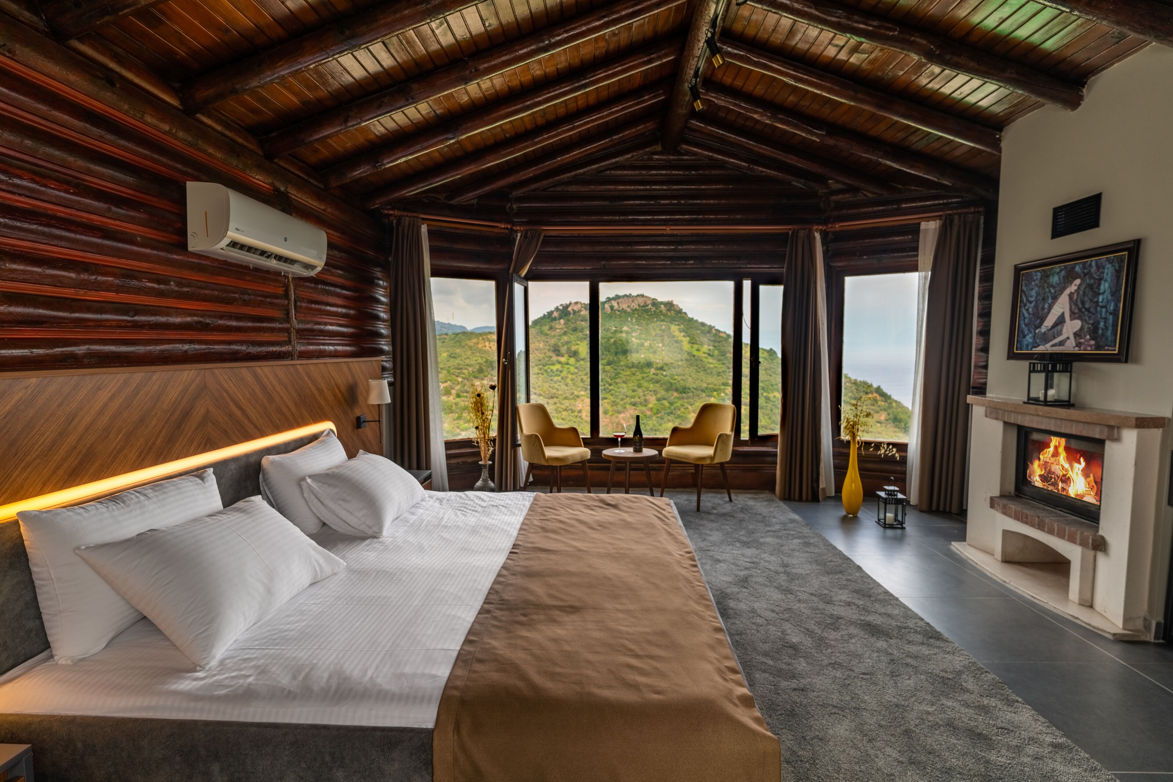 A bedroom with a large bed, a fireplace, and a view of a mountain.