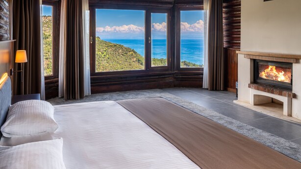 Une chambre avec un grand lit, une cheminée et une vue sur la mer.