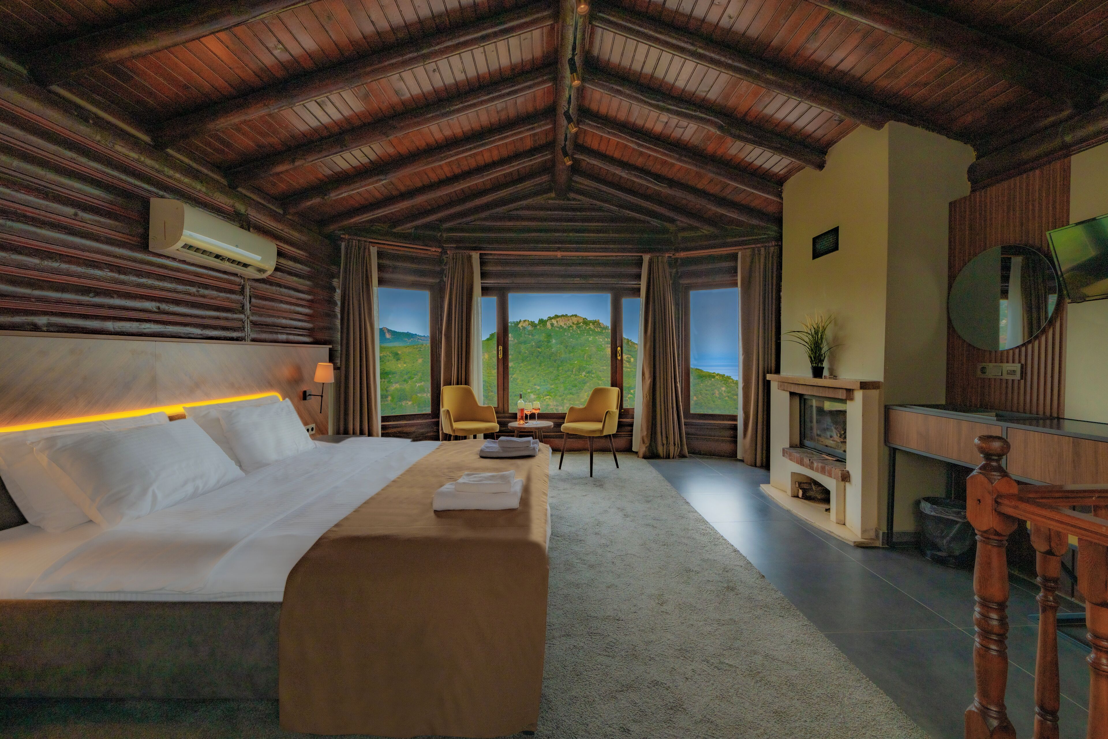 Une chambre spacieuse avec un grand lit, un plafond en bois et une vue sur l’extérieur.
