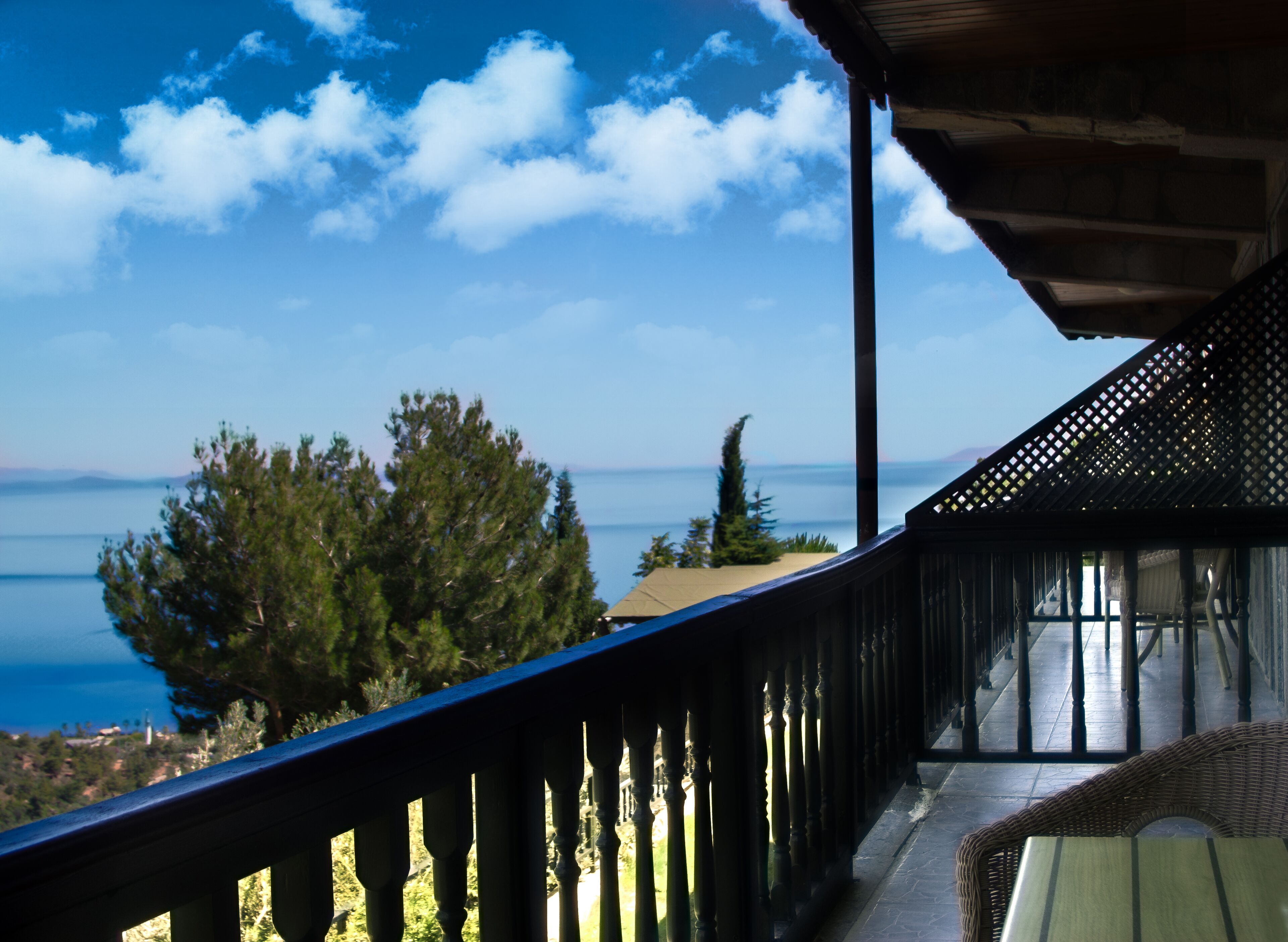 A balcony with a view of the sea and trees.