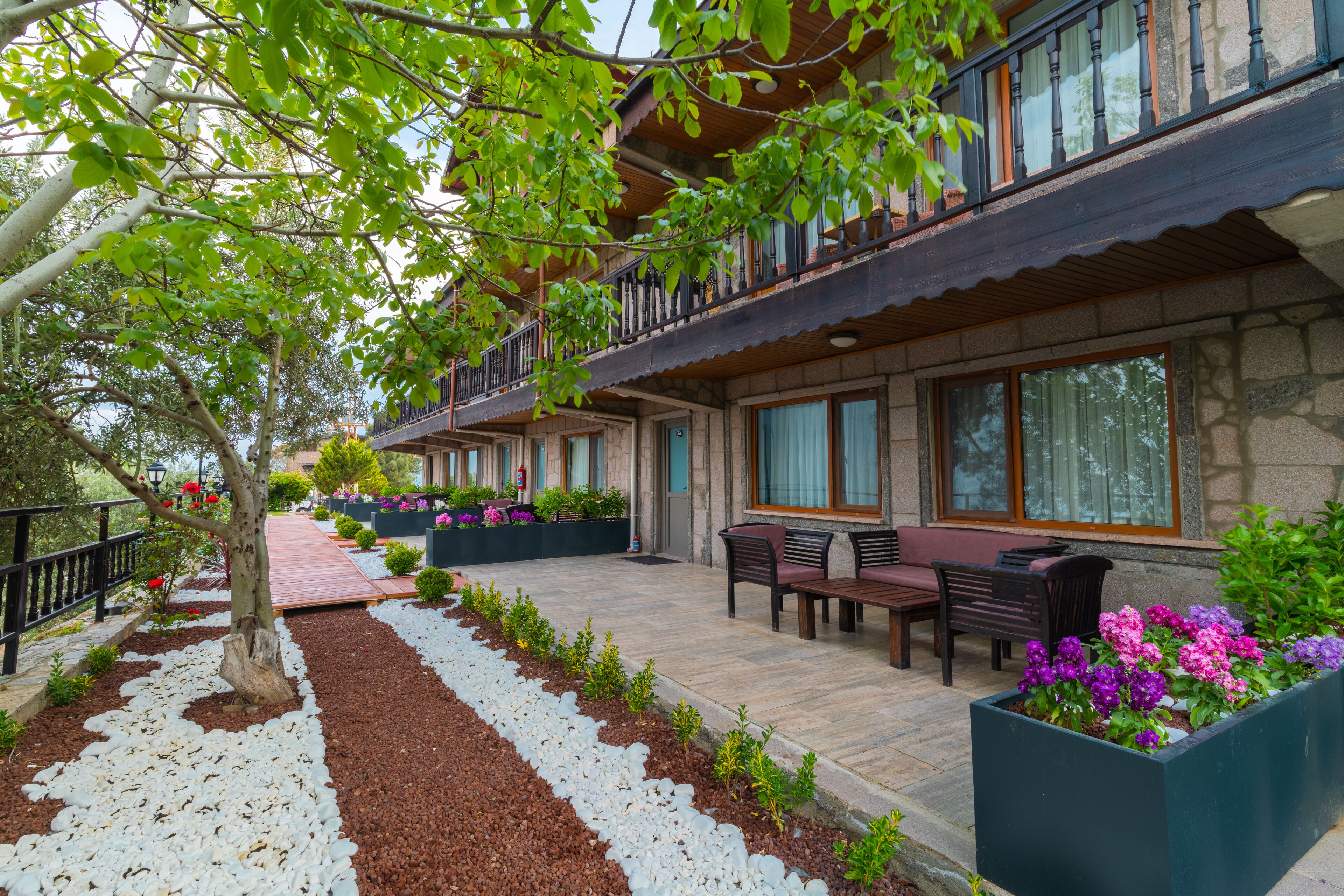 A hotel with a covered outdoor seating area, stone walls, and potted plants.