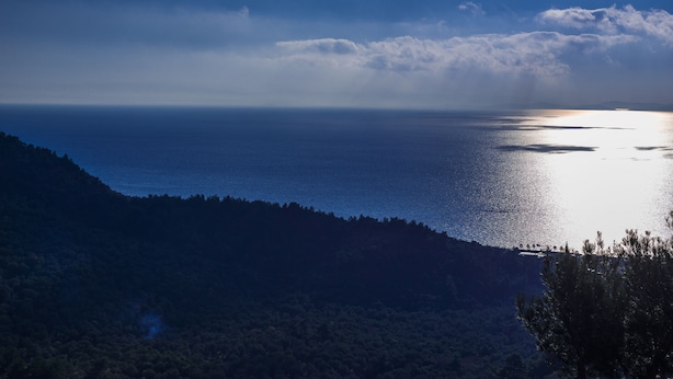 Un paysage côtier offrant une vue sur la mer et une colline boisée.