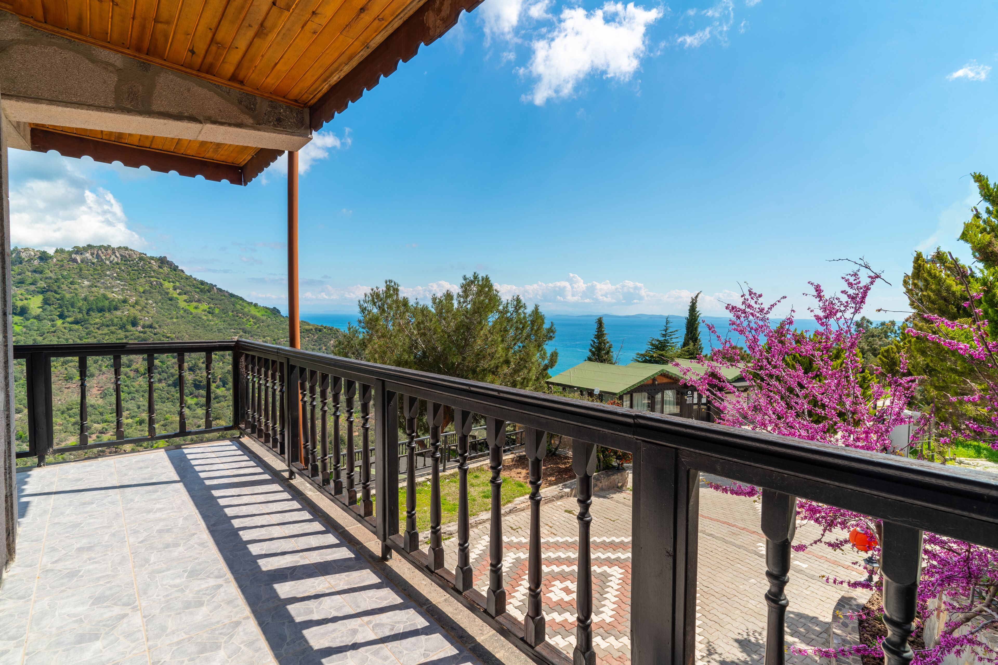 A balcony with a view of a mountainous landscape and a body of water.