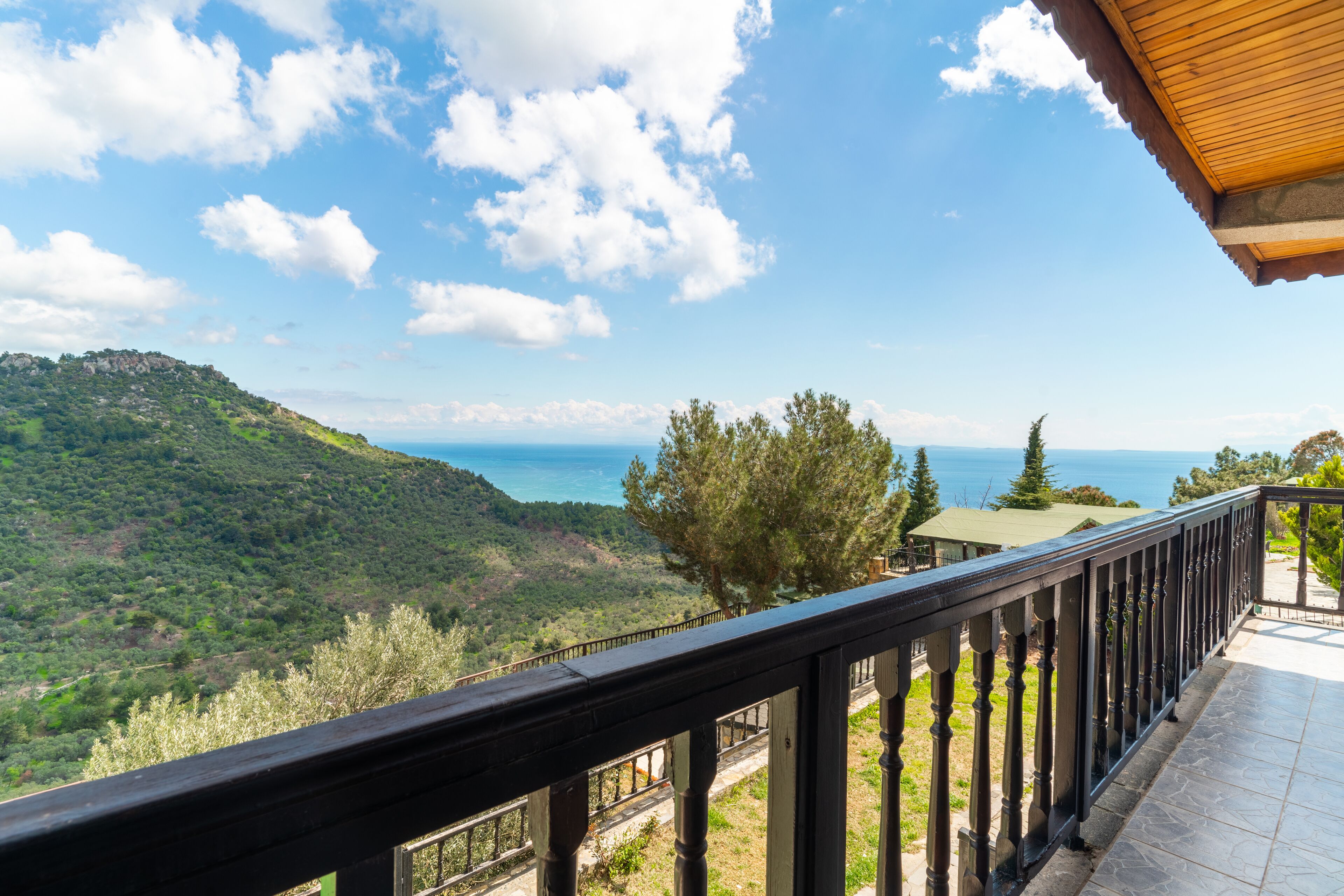 A balcony with a view of a mountainous landscape and the sea.