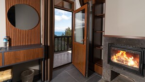 Une pièce moderne dotée d’une cheminée, d’un mur recouvert de panneaux de bois, d’un miroir rond et offrant une vue sur l’extérieur.