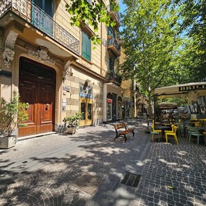 A cobblestone street with a café, a bench, and a building with a large wooden door and a sign that reads 'BRILLO'. - Wanda Bed&Breakfast (Naples)