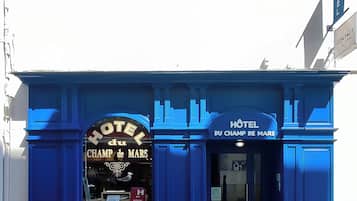 La façade d’un hôtel, sur laquelle on peut voir une enseigne bien visible indiquant « HÔTEL du CHAMP de MARS ».