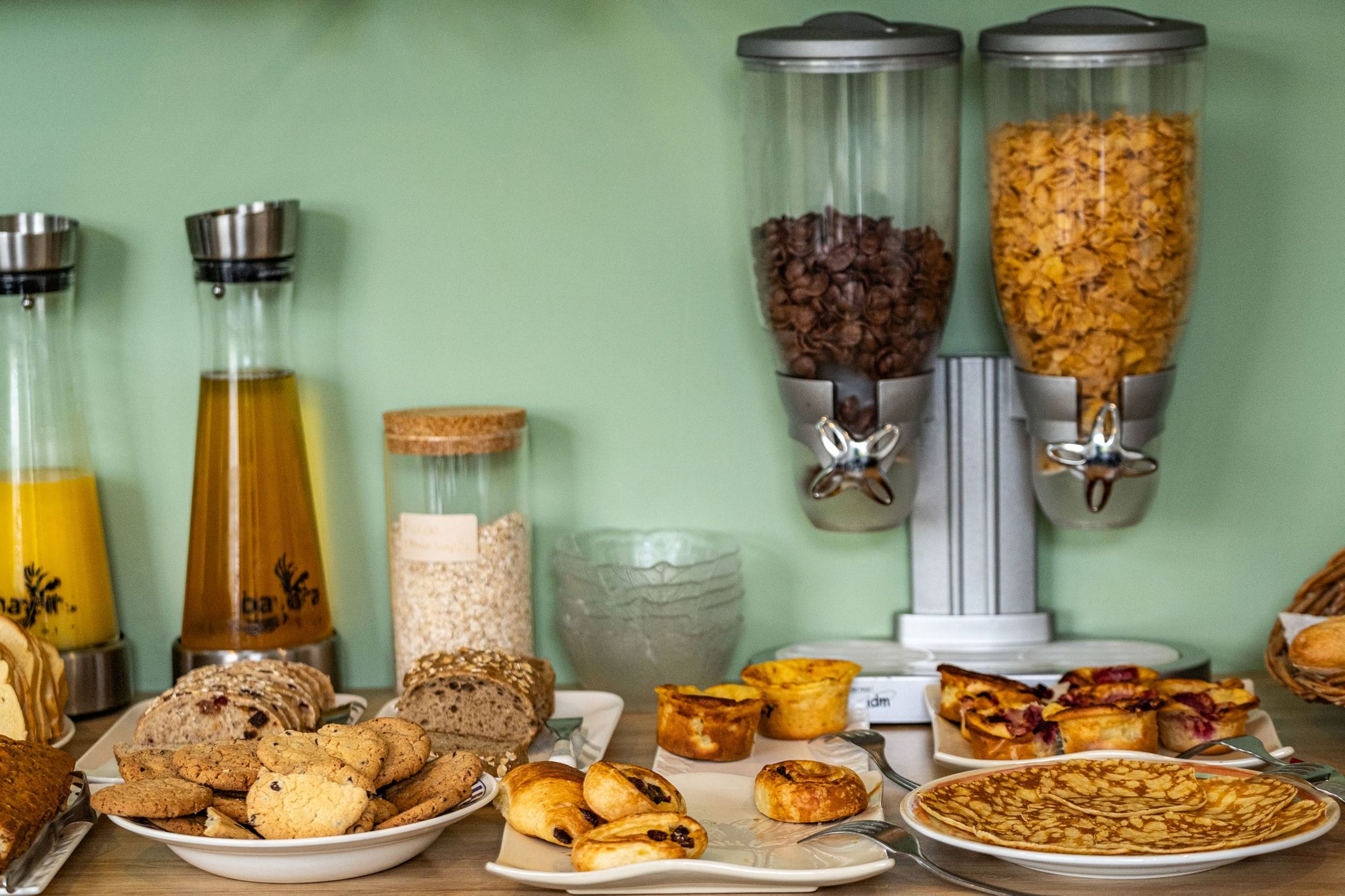 A breakfast buffet with various food items and drink dispensers.