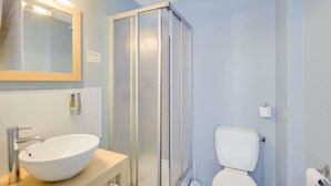 A bathroom with a white sink, mirror, and toilet, a glass shower enclosure, and a towel rack. - Hôtel du Champ de Mars (Saint-Brieuc)