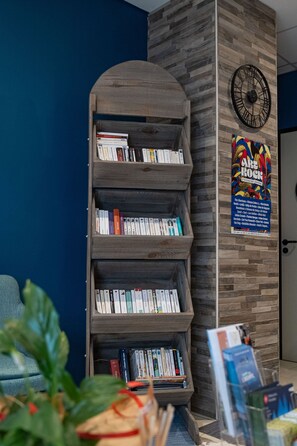 Una estantería con libros, un reloj y un póster en la pared.