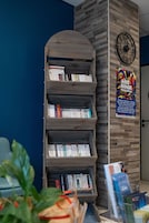 A bookshelf with books, a clock, and a poster on a wall.