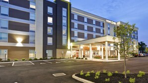 A modern hotel with a covered entrance, multiple floors, and a parking lot.