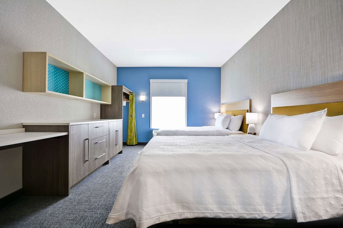 A hotel room with a bed, a desk, a wardrobe, and a bathroom visible through an open door.