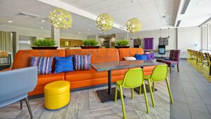 A modern lounge area with orange seating, a central table, and green chairs.