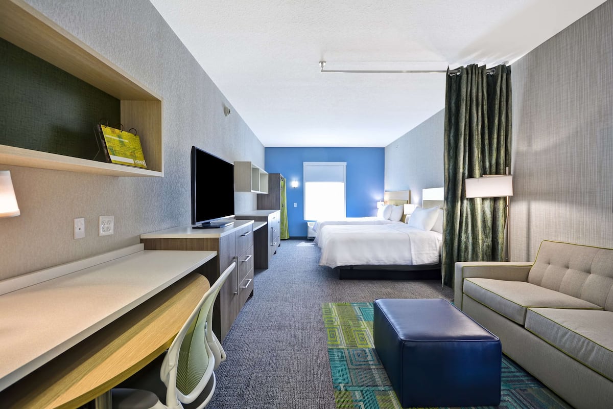 A hotel room with a desk, bed, and seating area.
