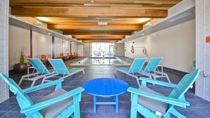 A pool area with lounge chairs and a table, wooden ceiling beams, and a view of the pool.