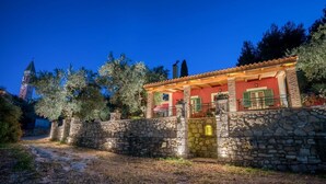 A stone-walled building with a red facade and a covered porch. - Villa Aelia (Zakynthos)