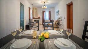 A dining area with a table set for two, a bottle of white wine, and a vase with flowers. - Villa Aelia (Zakynthos)